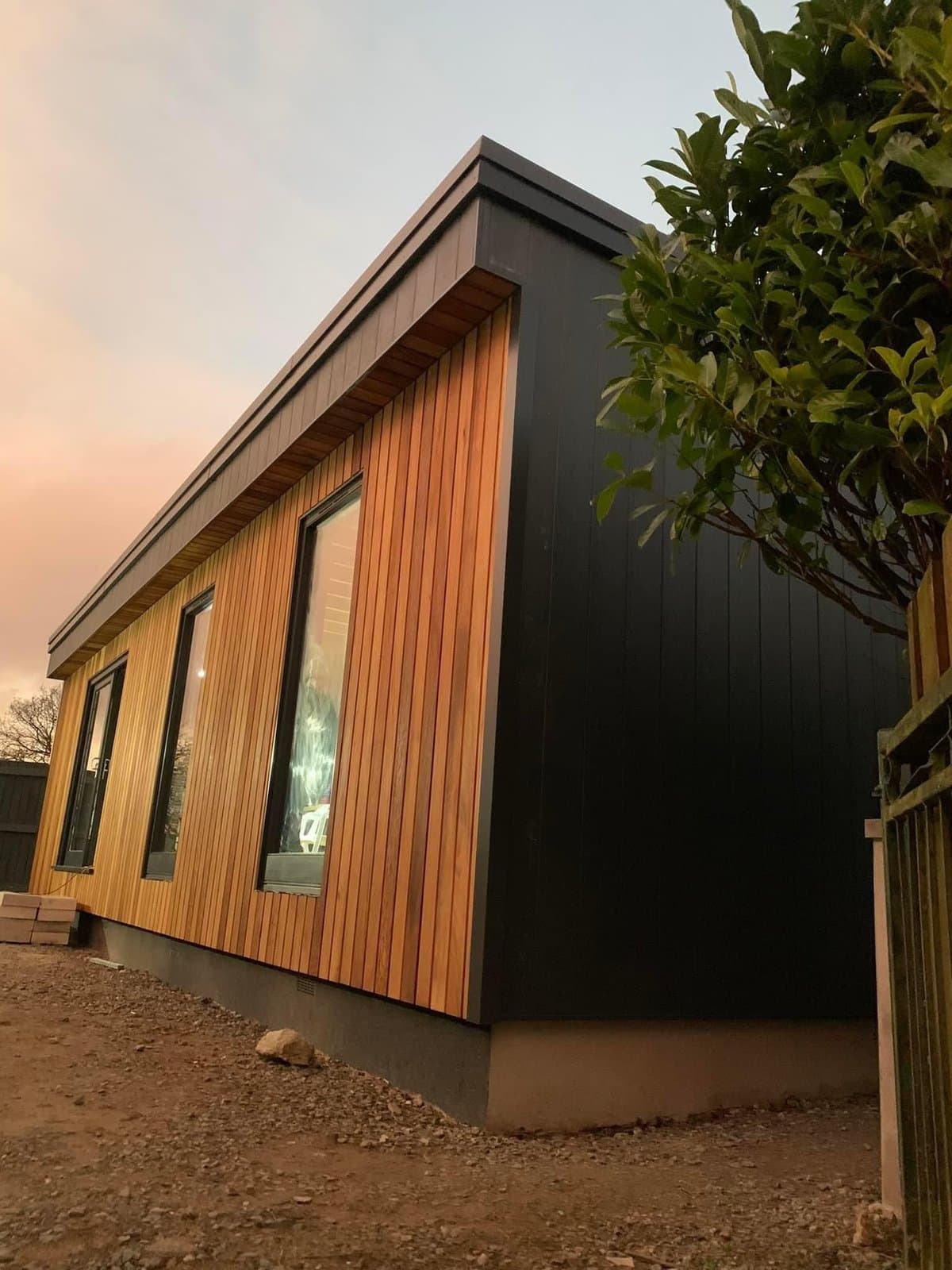 Finished cedar-clad annex with anthracite framing at sunset — PAS24-compliant new-build by K.Davey