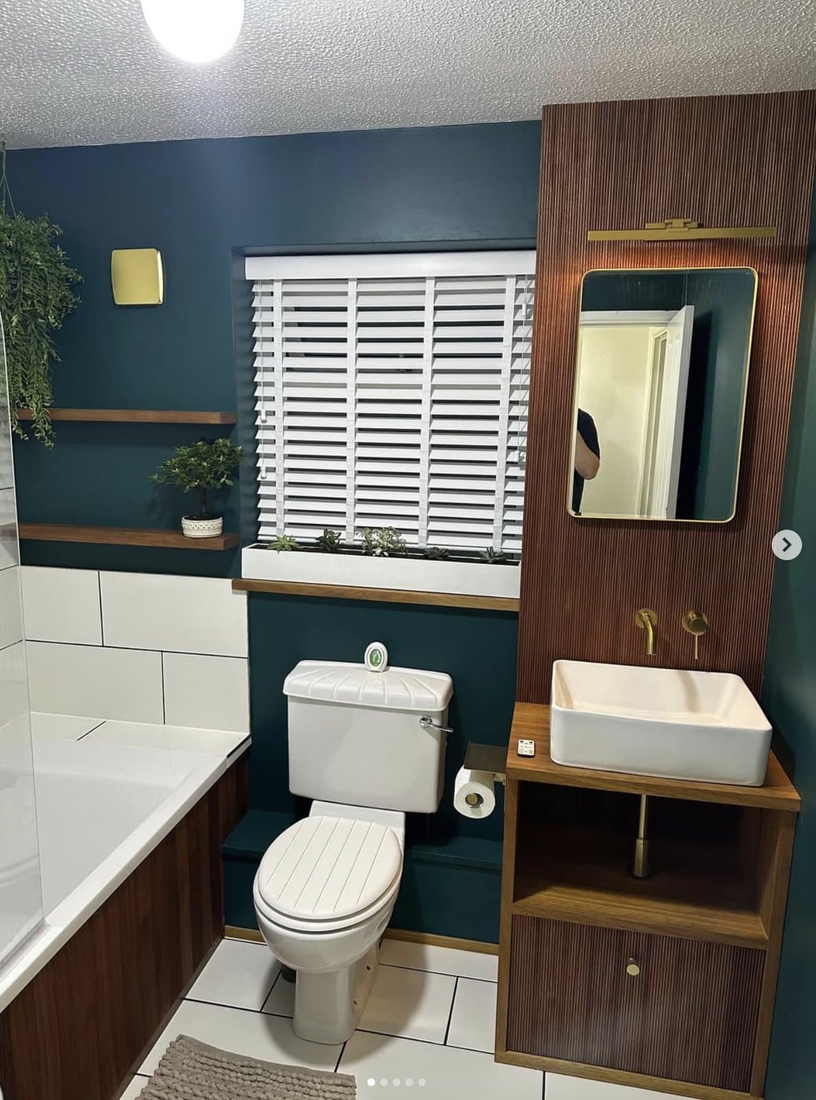 Same bathroom with bespoke timber vanity, matching bath panel, floating shelves and timber-framed mirror by K.Davey — bespoke fittings throughout with brass hardware
