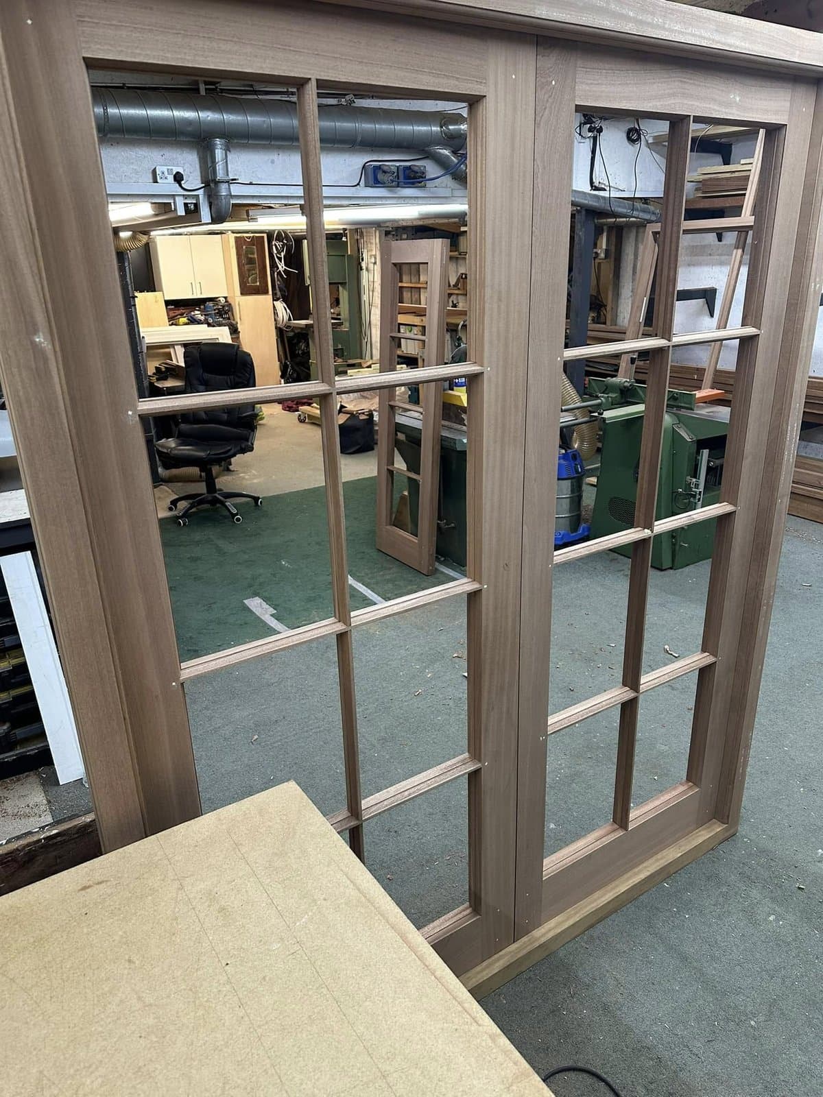 Glazed double doors with mullioned glass panels under construction in the workshop