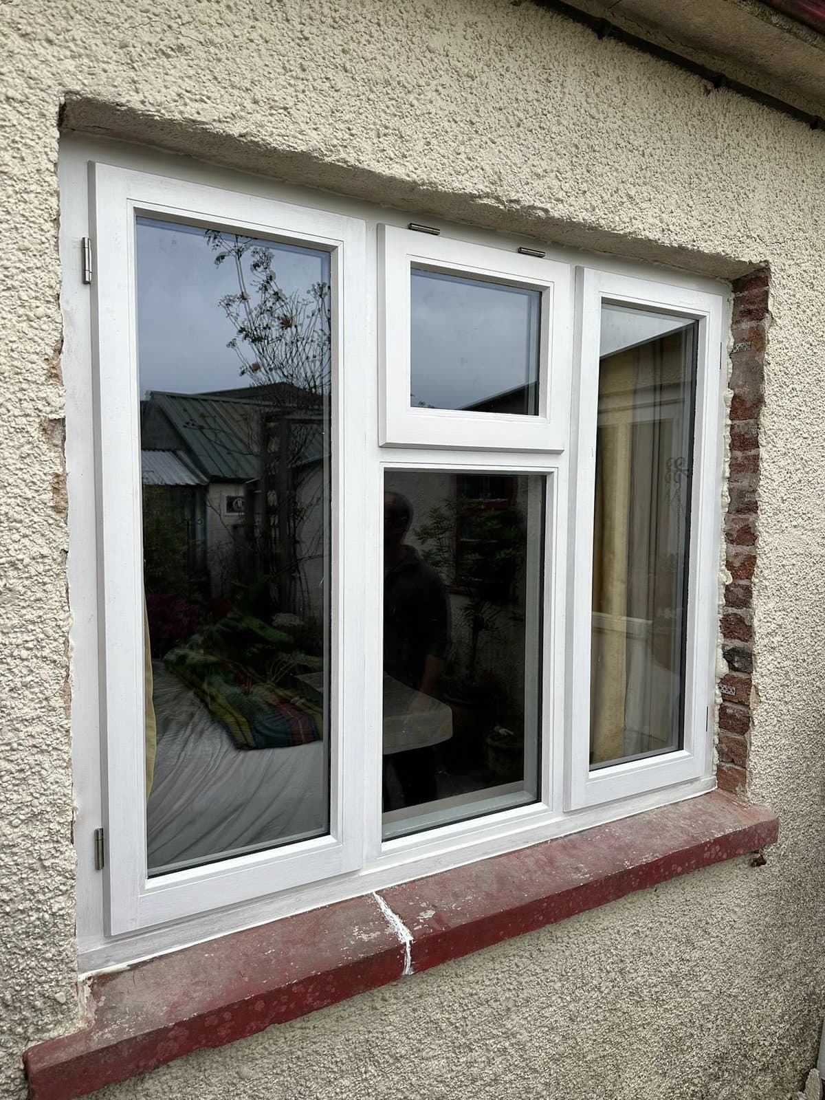 Bespoke white-painted timber three-pane casement window fitted into a stone cottage with a red brick sill — finished installation by K.Davey.