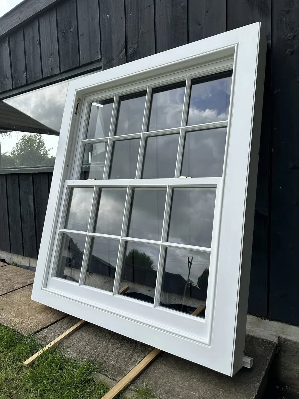 White-painted bespoke sash window standing against contemporary black timber cladding
